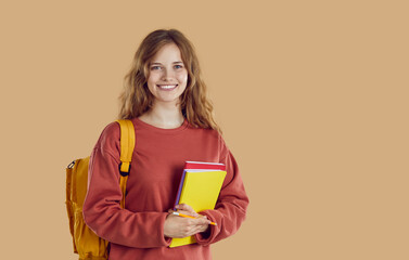 Portrait of happy smiling student girl with yellow backpack and folders in red sweatshirt on beige background. Happy cheerful woman with wavy light hair. Banner with copy space for advertisement.