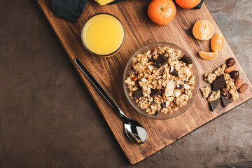 Granola cereal oatmeal with chocolate, fruist and nuts in a bowl on dark wooden board, top view