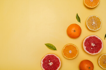 Citrus fruits on a yellow background with copyspace, fruit flatley, a summer minimalist composition with grapefruit, lemon, tangerine and orange.