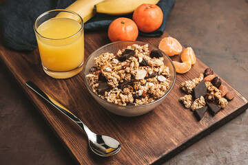 Granola cereal oatmeal with chocolate, banana and nuts in a bowl on dark wooden board