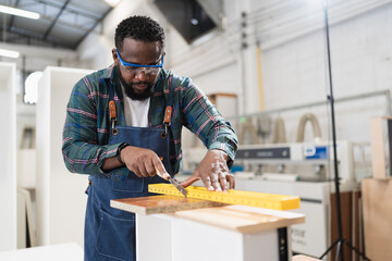 African American carpenter use Precision level to wood at wood factory	
