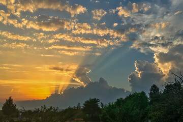 Rare sunset with rays of light behind clouds