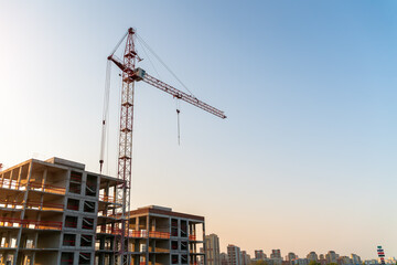 Construction crane on the background of a house under construction. Sunset
