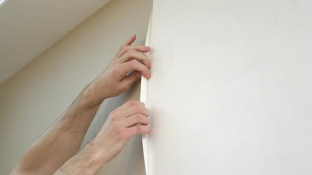 man easily removes the wallpaper from the wall. home renovation by yourself