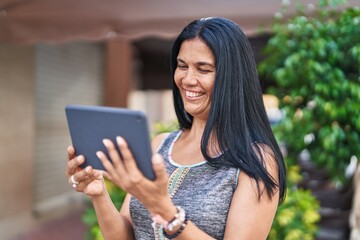 Obraz premium Middle age hispanic woman smiling confident using touchpad at street