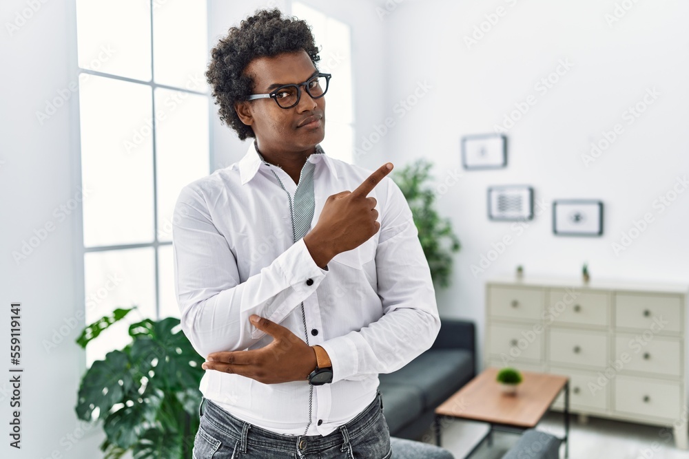 Wall mural african psychologist man at consultation office pointing with hand finger to the side showing advert