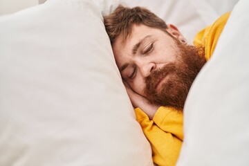 Young redhead man lying on bed sleeping at bedroom