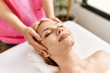 Fototapeta na wymiar Young caucasian woman lying on table having head massage at beauty salon