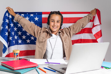 little girl cheering with American flag. Education online on laptop computer. Pupil in class