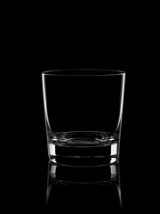 An empty glass for whiskey on a black background, on a dark mirror surface. Studio shot. Vertical.