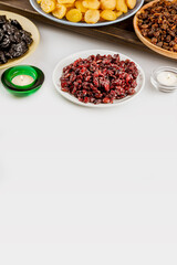 Ramadan food vertical banner with dried apricots, cranberries, raisins, and prunes on plates on white background with copy space. Dry fruits assortment. Healthy sweet snack - mix of organic dry fruits