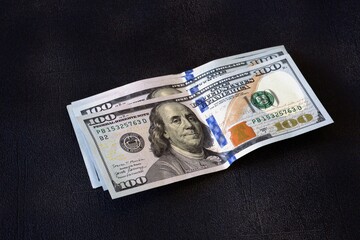 American dollar bills lying on the table are dark in color.