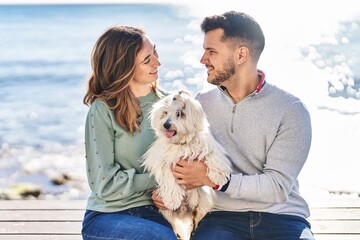 Man and woman holding dog hugging each other at seaside