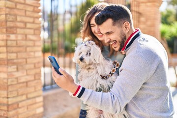 Man and woman holding dog having video call by smartphone at street