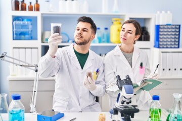Man and woman wearing scientist uniform working at laboratory