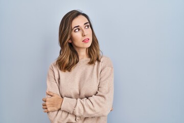 Obraz premium Young woman standing over isolated background looking to the side with arms crossed convinced and confident