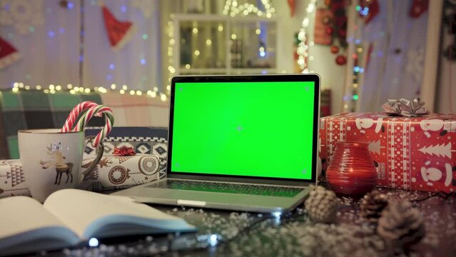 Laptop with green screen at Christmas workplace. Holidays and celebrations time. New Year 2023.