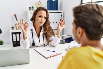 Young doctor woman showing electronic cigarette and normal cigarrete to patient relaxed with serious expression on face. simple and natural looking at the camera.