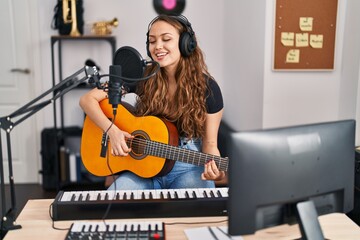 Fototapeta na wymiar Young beautiful hispanic woman musician singng song playing classical guitar at music studio