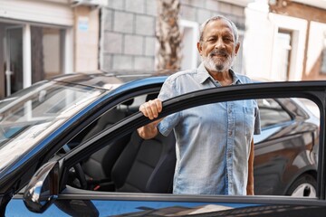 Senior grey-haired man smiling confident opening car door at street
