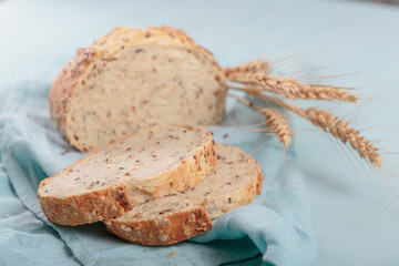 Sliced fresh baked whole grain bread with flax seeds and sesame seeds on light blue board. Bakery products