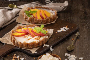 Nectarine vegan tarts with grated coconut and crunchy peanuts. Date, walnut, almond and hazelnut base.