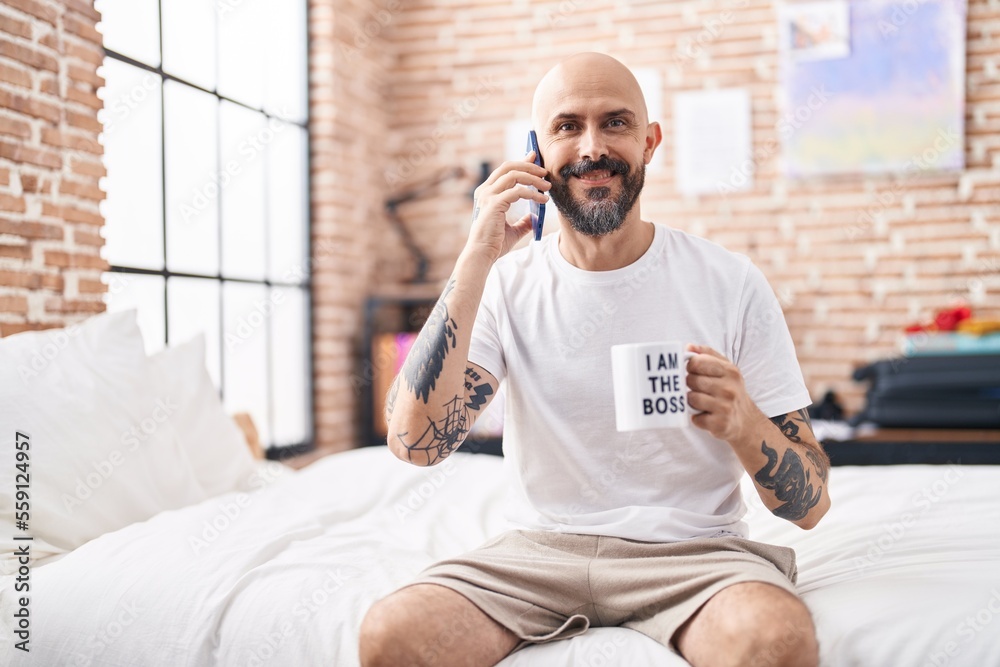 Sticker Young bald man talking on smartphone drinking coffee at bedroom