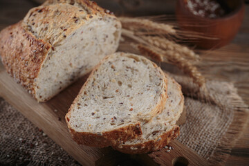 Sliced fresh baked whole grain bread with oats, flax seeds and sesame seeds on rustic wooden board. Bakery products