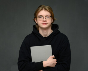 Caucasian guy portrait student with folder on gray background looking at camera