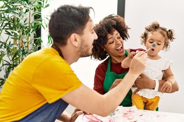 Couple and daughter smiling confident painting child nose at art studio
