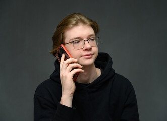 Young guy talking on the phone on a gray background - 559125912