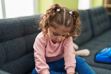 Adorable caucasian girl sitting on sofa with relaxed expression at home