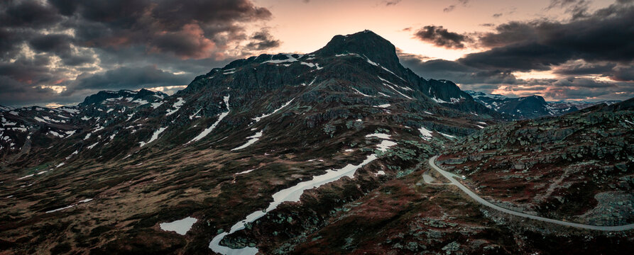 Mountain landscape with summit of Bitihorn in Jotunheimen National Park, with road leading through the park, during sunset in Norway