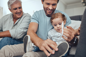 Family, love and dad with child on sofa to tie shoes laces enjoying weekend, quality time and bonding together. Family home, support and grandfather, father and boy relaxing on couch in living room