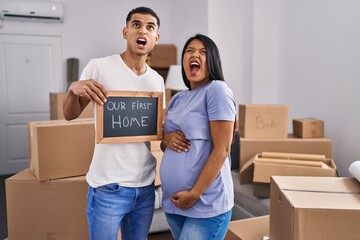 Young hispanic couple expecting a baby moving to a new home angry and mad screaming frustrated and...