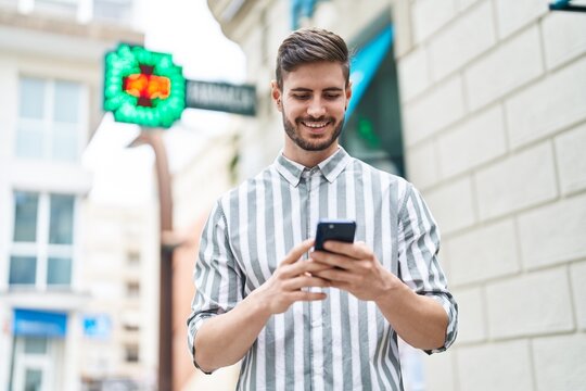 Young caucasian man smiling confident using smartphone at pharmacy