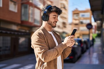 Young hispanic man smiling confident listening to music at street