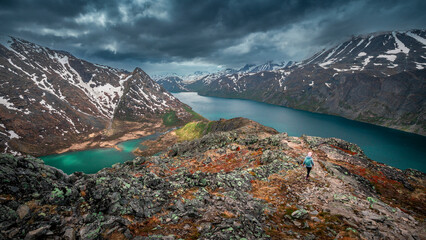 Woman hiking along turquoise and blue lakes in mountain landscape on hike of Knutshoe in...