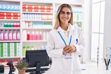 Young blonde woman pharmacist smiling confident standing at pharmacy