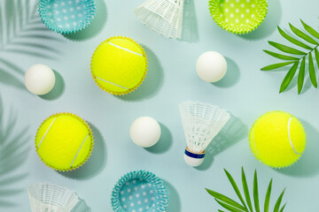 Summer sport activities card with yellow tennis balls, table tennis balls and shuttlecocks on blue background with palm leaves and shadows. Sport and healthy lifestyle. Tennis, table tennis, badminton