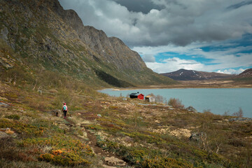 Woman hiking at turquoise lake surrounded by mountain landscape at Knutshoe summit in Jotunheimen...