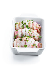 Raw Chicken breasts wrapped in bacon in white dish isolated on white. Ready to cook