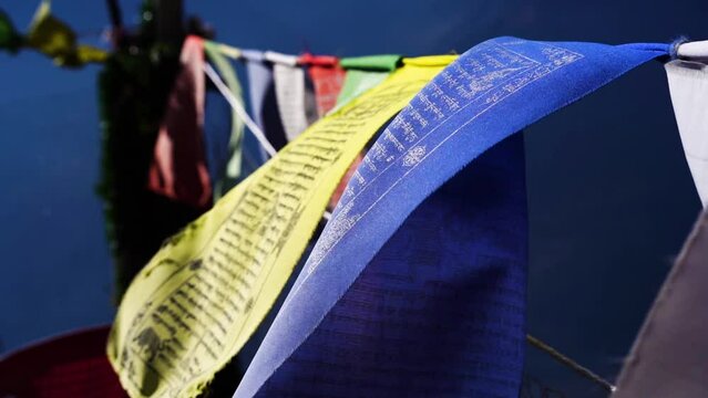 slow motion macro shot sacred religious multicolored prayer flags moving in the wind showing a bhuddist prayer incantation common in hill stations in Himachal Pradesh India
