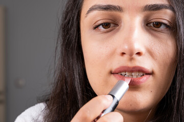 Obraz premium Woman holds lipstick, close up image of woman holds lipstick. Rouging color on lips. Applying make up using professional cosmetics. Peeling cracking cold season protection balm. Morning beauty routine