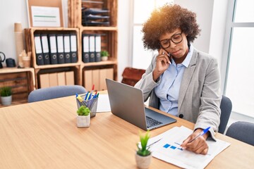 African american woman business worker talking on smartphone writing on document at office