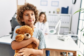 Mother and son smiling confident hugging teddy bear at clinic