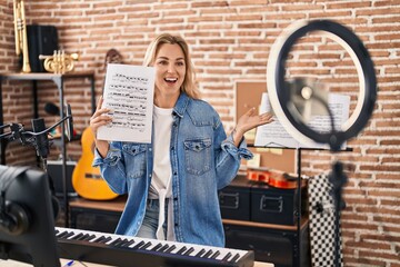 Young caucasian woman doing online music tutorial showing music sheet celebrating achievement with...