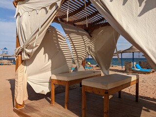 wooden massage tent with white curtains by the sea
