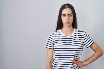 Young brunette woman wearing striped t shirt skeptic and nervous, frowning upset because of problem. negative person.