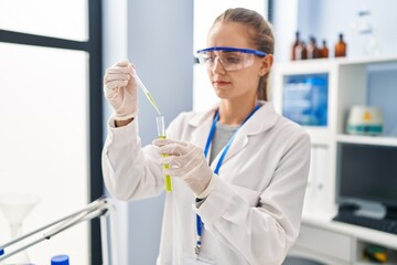 Young blonde woman wearing scientist uniform working at laboratory